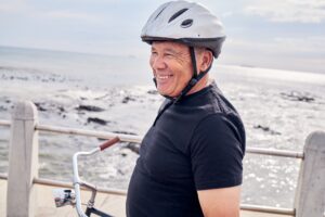 Happy, senior and man by the beach for cycling, training and eco friendly travel in Portugal. Fitne